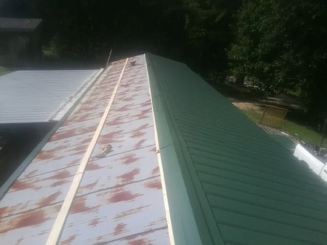 Old rusted panels beside newly installed green metal roofing — Wind Damage Roof Repair by Roofing Brothers in Middle Haddam