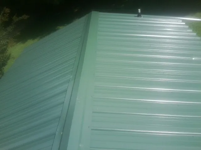 New green metal panels meeting at the ridge of a roof — Flat Roof Repair work by our crew in Middle Haddam