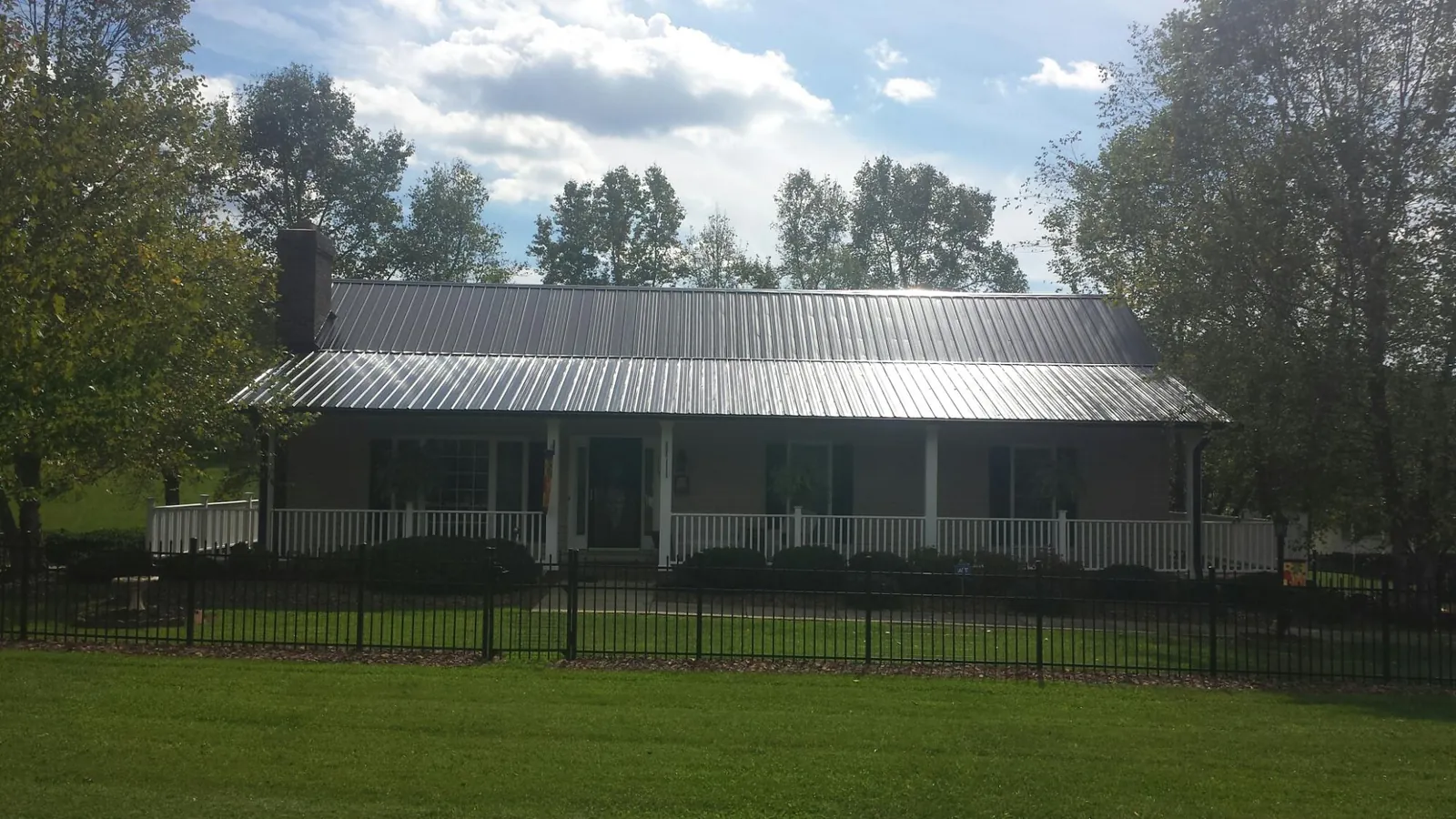 Gray metal roof on a brick ranch with a full width front porch — Gutter Guard Installation work by our crew in Middle Haddam