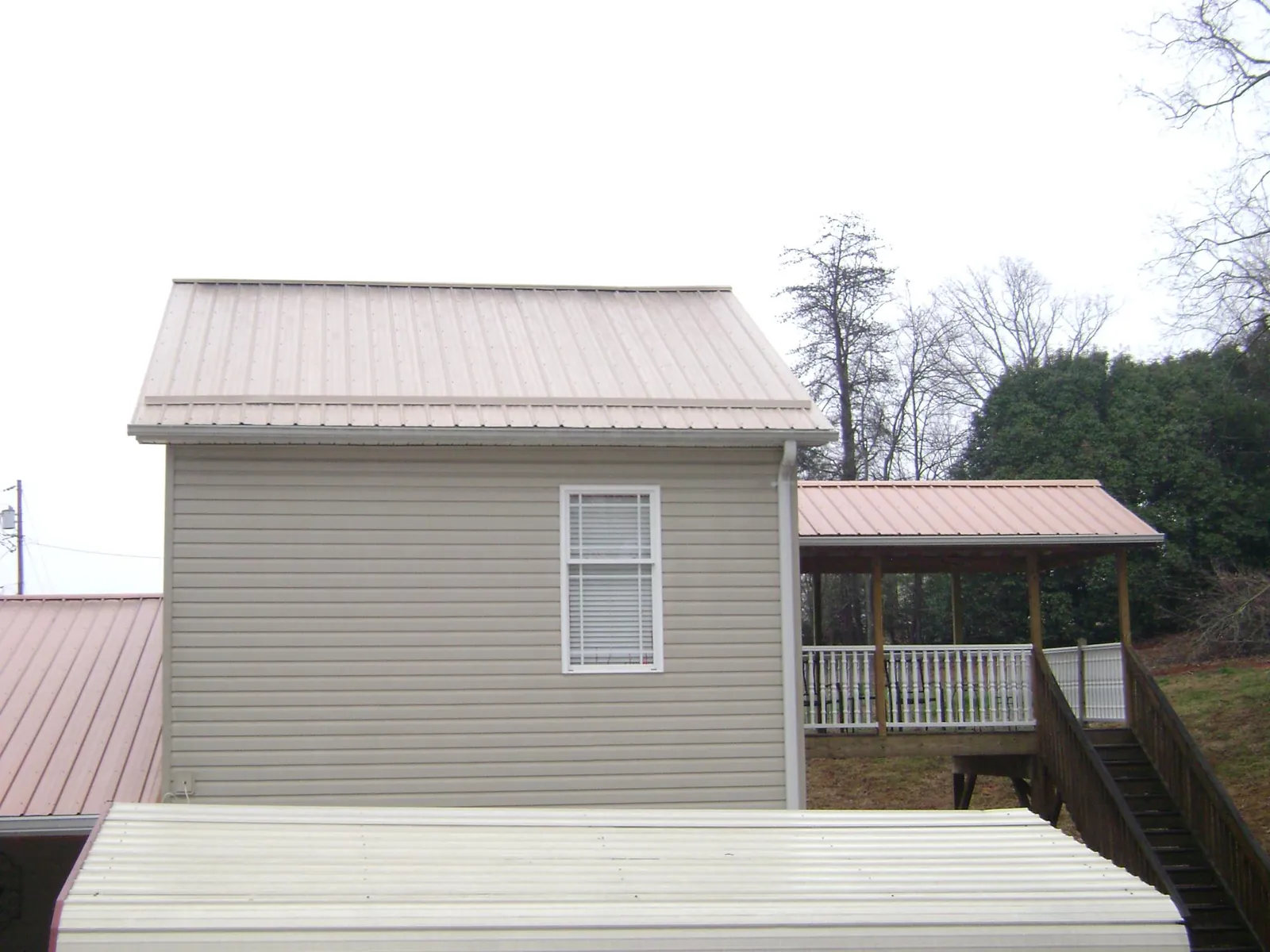Tan metal roofs on a two story addition and attached porch, from a Roof Replacement job in Middle Haddam
