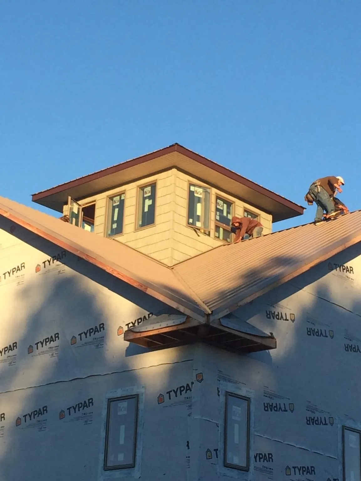 Roofers working around a rooftop cupola on a new metal roof at sunset — Roof Waterproofing in Middle Haddam by Roofing Brothers